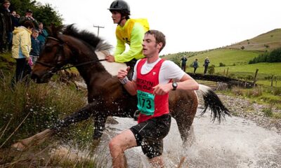 Runner and horse competing side-by-side in the unique Man vs Horse race through the Welsh countryside.