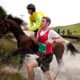 Runner and horse competing side-by-side in the unique Man vs Horse race through the Welsh countryside.