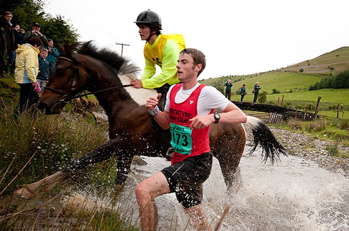 Runner and horse competing side-by-side in the unique Man vs Horse race through the Welsh countryside.