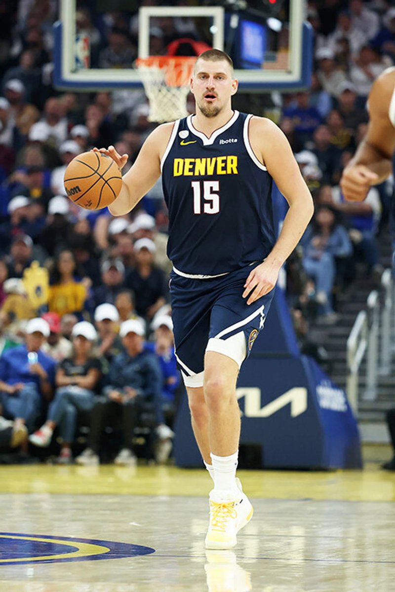 Nikola Jokić dribbling the basketball during an NBA game for his back-to-back triple-double performance.