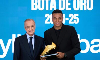 Kylian Mbappe holding the 2025 Golden Boot award on the pitch at Real Madrid's Santiago Bernabeu stadium.